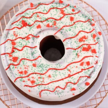 Delicious festive cake with white icing, red and green sprinkles, and decorative red icing. Perfect for holidays.