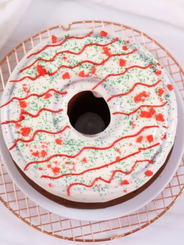 Delicious festive cake with white icing, red and green sprinkles, and decorative red icing. Perfect for holidays.