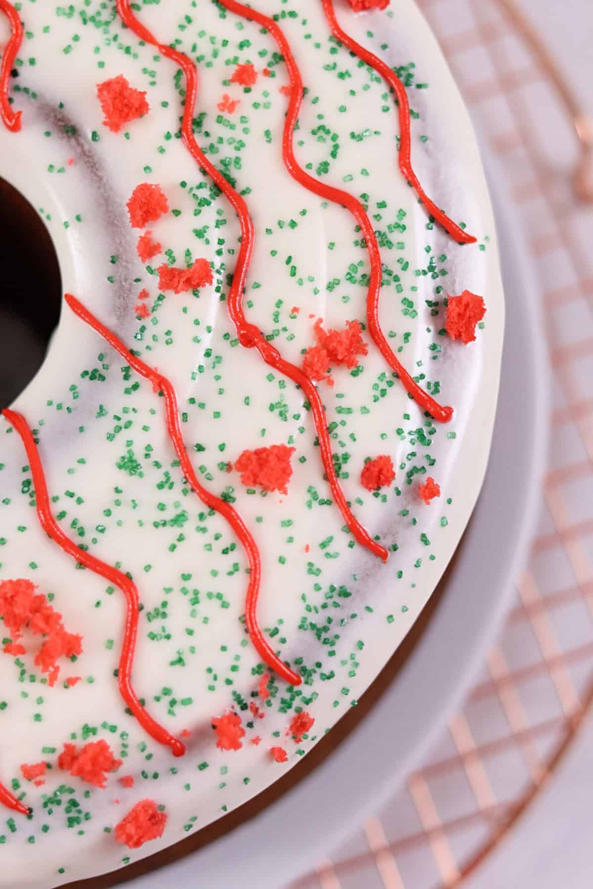 Close-up of decorated festive cake with white icing, red and green sprinkles, and red piped icing.