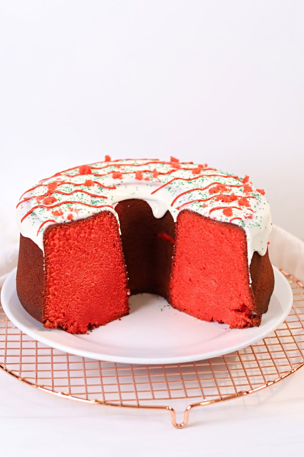 Delicious red velvet cake with white frosting, red and green sprinkles, ready for holiday festivities.