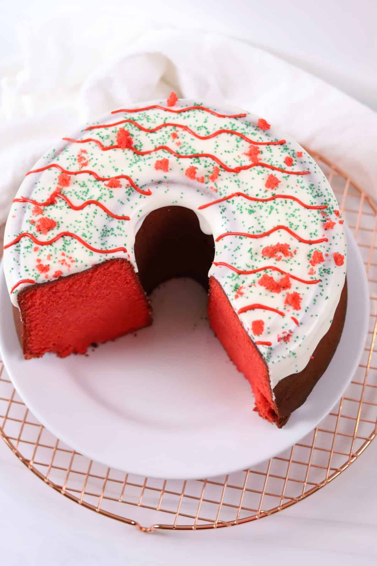 A holiday-themed red and white cake decorated with colorful icing and sprinkles, perfect for Christmas celebrations.