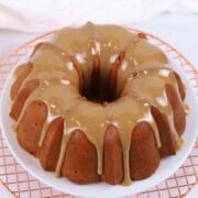 Bundt cake with caramel glaze and white icing drizzle on a wire rack.