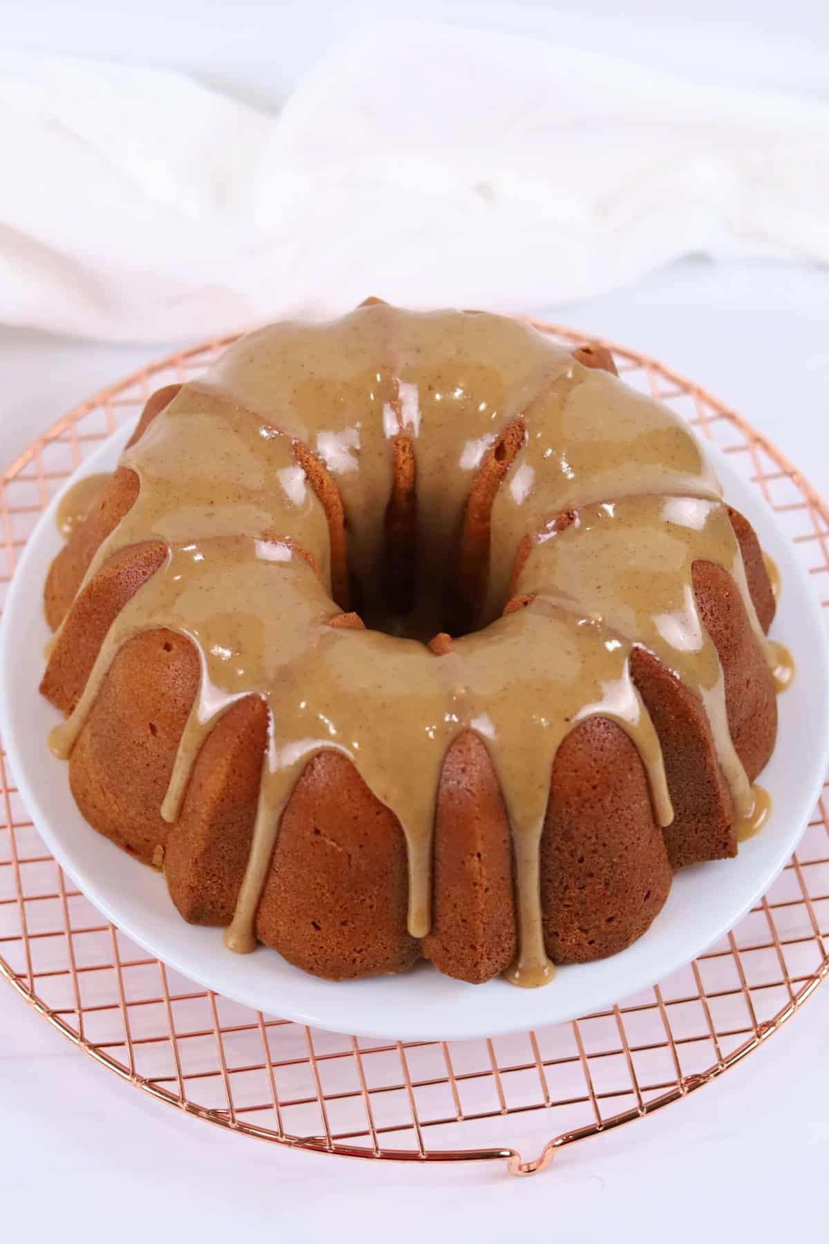 Bundt cake with caramel glaze and white icing drizzle on a wire rack.